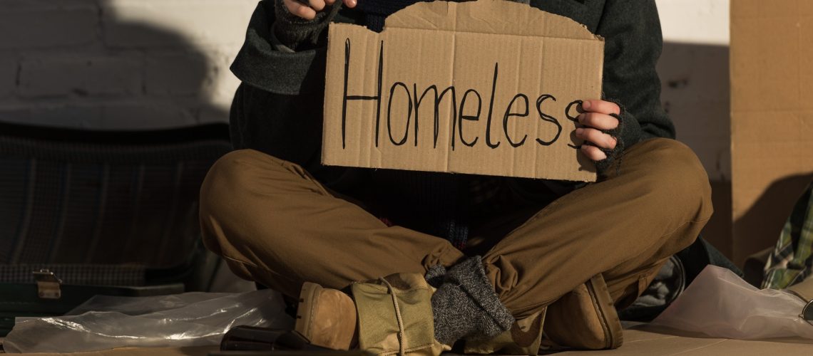 cropped-view-of-homeless-man-holding-piece-of-cardboard-with-homeless-handwritten-inscription.jpg