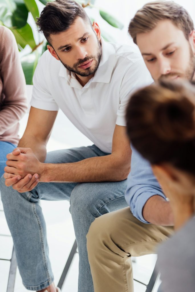 selective focus of men sitting during group therapy session